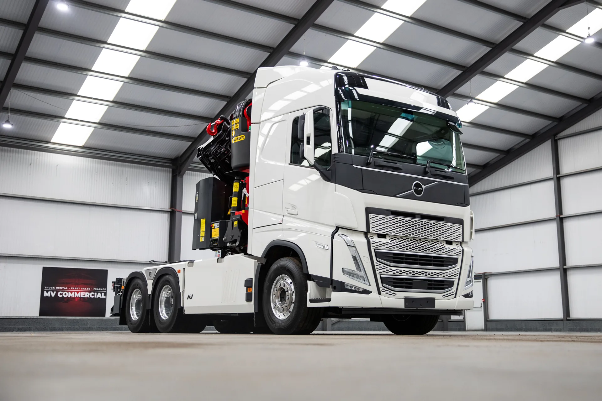 A white Volvo FH crane truck in the MV Commercial workshop.